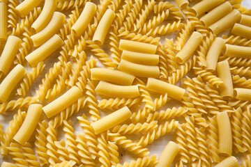 Top view image of Macaroni pasta. Raw pasta as background, close up. Italian wheat pasta on a white table, background texture, healthy food. High quality photo