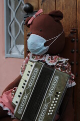 Funny taddy bear in medical mask playing the accordion - obrazy, fototapety, plakaty