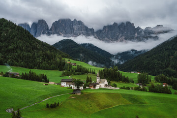 Fototapeta na wymiar St Magdalena church in Val di Funes valley, Dolomites, Italy. Furchetta and Sass Rigais mountain peaks in background