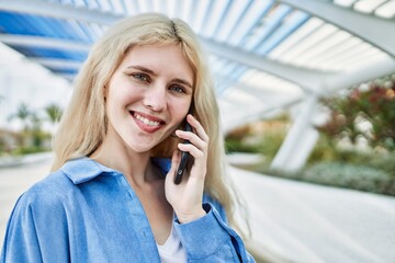 Young blonde woman outdoors on a sunny day speaking on the phone