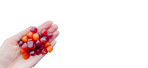 Group of red, orange and purple multivitamin gummies in the hand isolated on white background
