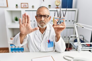 Fototapeta na wymiar Mature doctor man holding model of human anatomical skin and hair with open hand doing stop sign with serious and confident expression, defense gesture