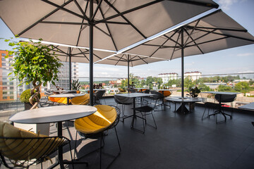 Bright garden furniture and plants on cozy terrace with wooden floor and brick wall. Interior of a summer terrace of a restaurant