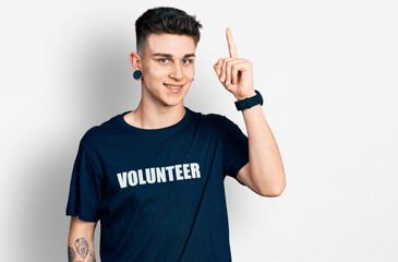 Young caucasian boy with ears dilation wearing volunteer t shirt pointing finger up with successful...