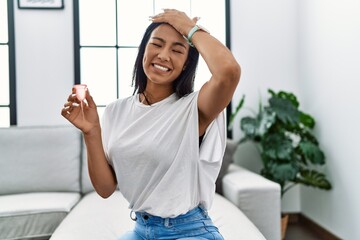 Young hispanic woman holding menstrual cup stressed and frustrated with hand on head, surprised and angry face