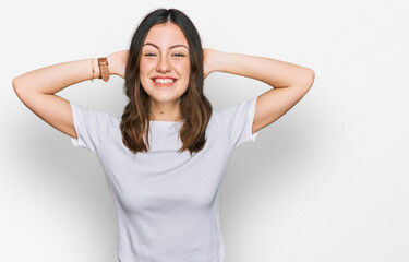 Young beautiful woman wearing casual white t shirt relaxing and stretching, arms and hands behind head and neck smiling happy