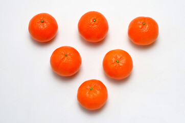 ripe tangerines laid out in the shape of a triangle on a white background