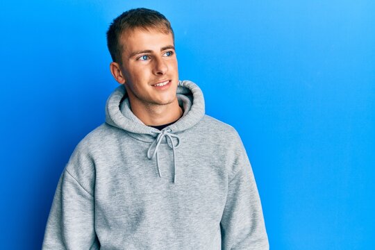 Young caucasian man wearing casual sweatshirt looking to side, relax profile pose with natural face and confident smile.