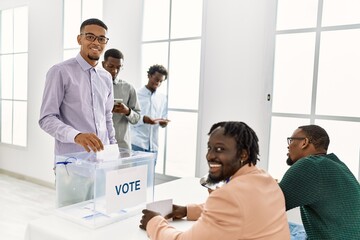 Group of young african american voter people putting vote in ballot standing at electoral center.