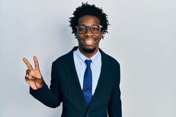 Young african american man wearing business suit smiling with happy face winking at the camera doing victory sign. number two.