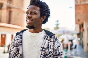 Fototapeta premium Handsome black man with afro hair and beard smiling happy outdoors