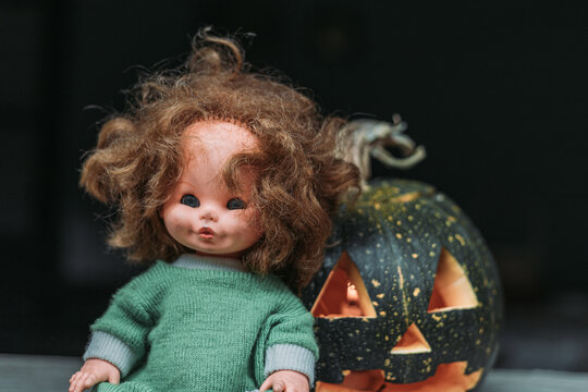 Close-up of carved pumpkin with old, vintage doll. Halloween decoration concept