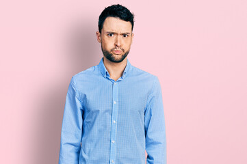 Hispanic man with beard wearing casual business shirt puffing cheeks with funny face. mouth...