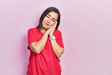 Middle age hispanic woman wearing casual clothes sleeping tired dreaming and posing with hands together while smiling with closed eyes.