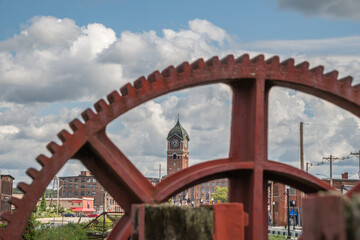 Red industrial gears with nineteenth century brick mill building in background