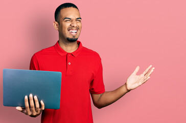 Young african american man working using computer laptop celebrating victory with happy smile and winner expression with raised hands