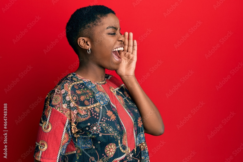 Sticker young african american woman wearing african style shouting and screaming loud to side with hand on 