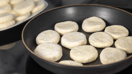 Cooking at home concept, frying cheese pancakes in iron pan, selective focus