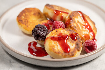 Close cottage cheese pancakes with raspberry and berry syrup, curd fritters portion on plate
