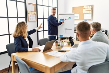 Obraz premium Group of middle age business workers listening boss conference during meeting at the office.