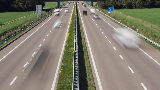 Time-lapse of cars and trucks driving on a straight highway in swiss countryside