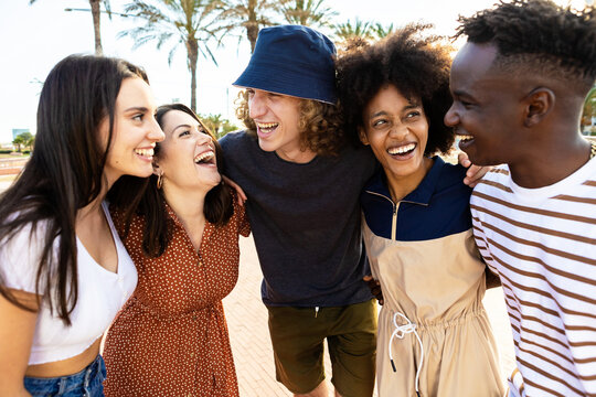 United Young Adult Friends Laughing Together - Multiracial Happy People Having Fun Outdoors - Smiling Hipster Students Hugging Each Other While Celebrating - Youth, Community And Unity Concept