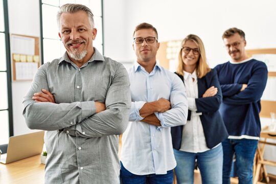Group of middle age business workers smiling happy standing with arms crossed gesture at the office.