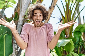 Young hispanic man outdoors on a sunny day celebrating victory with happy smile and winner expression with raised hands