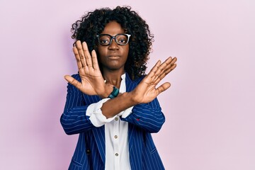 Young african american woman wearing business clothes and glasses rejection expression crossing...