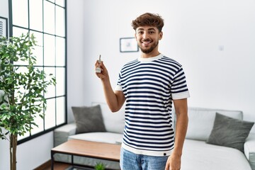 Young arab man smiling confident holding key of new house at home