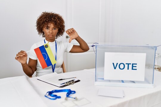 Young african american woman at political campaign election holding venezuela flag with angry face, negative sign showing dislike with thumbs down, rejection concept