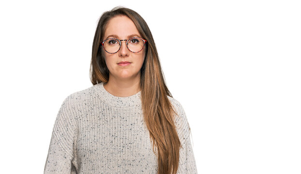 Young blonde woman wearing casual sweater and glasses relaxed with serious expression on face. simple and natural looking at the camera.