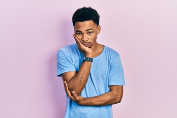 Young african american man wearing casual blue t shirt thinking looking tired and bored with depression problems with crossed arms.