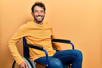 Handsome man with beard sitting on wheelchair with a happy and cool smile on face. lucky person.