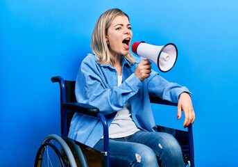 Blonde woman sitting on wheelchair screaming through megaphone over isolated background