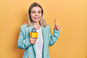 Beautiful caucasian woman holding reporter microphone smiling with an idea or question pointing...