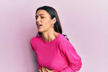 Young hispanic woman wearing casual clothes with hand on stomach because nausea, painful disease feeling unwell. ache concept.