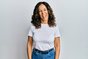 Middle age hispanic woman wearing casual white t shirt winking looking at the camera with sexy...