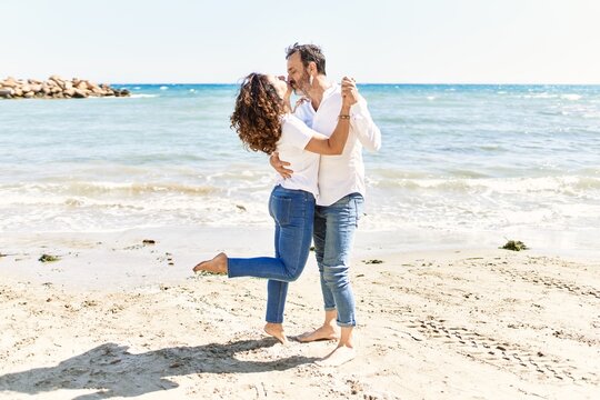 Middle age hispanic couple kissing and hugging at the beach.