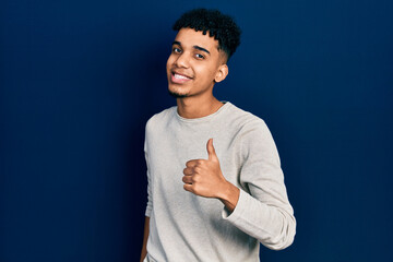 Young african american man wearing casual clothes doing happy thumbs up gesture with hand. approving expression looking at the camera showing success.