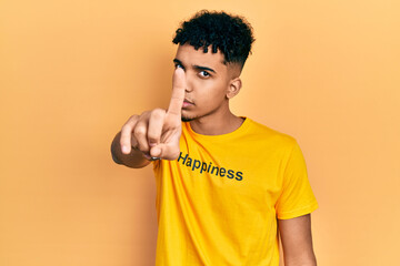 Young african american man wearing t shirt with happiness word message pointing with finger up and angry expression, showing no gesture