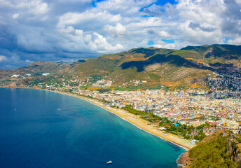 Fototapeta premium sunny view of Alanya and the port against the backdrop of mountains and clouds in autumn