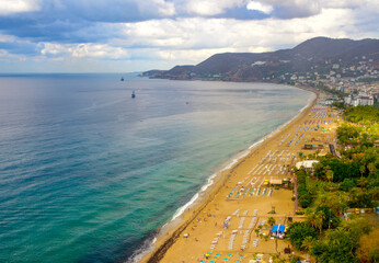 sunny view of Alanya and the port against the backdrop of mountains and clouds in autumn