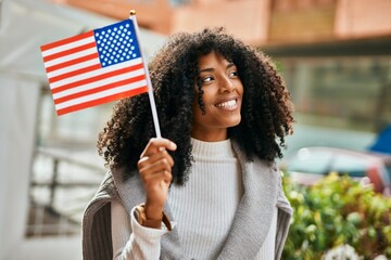 Young african american woman smiling happy holding United States flag at the city. - Powered by Adobe