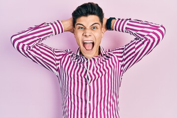 Young hispanic man wearing casual clothes crazy and scared with hands on head, afraid and surprised of shock with open mouth