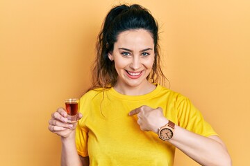 Young hispanic woman drinking whiskey shot pointing finger to one self smiling happy and proud