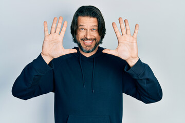 Middle age caucasian man wearing casual sweatshirt showing and pointing up with fingers number ten while smiling confident and happy.