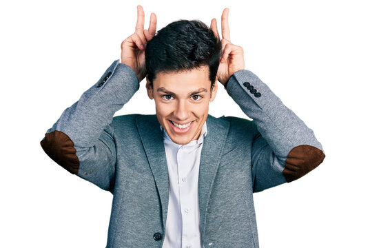 Young hispanic man wearing business clothes posing funny and crazy with fingers on head as bunny ears, smiling cheerful