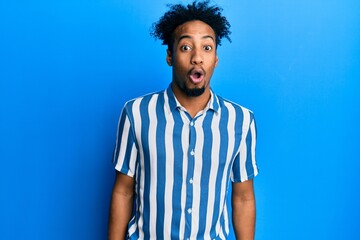 Fototapeta na wymiar Young african american man with beard wearing casual striped shirt afraid and shocked with surprise expression, fear and excited face.