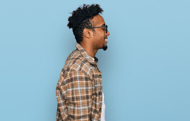 Young african american man with beard wearing casual clothes and glasses looking to side, relax profile pose with natural face and confident smile.